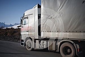 White refrigerated truck on winter road on background of the mountains