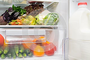 In the White refrigerator on the shelves, fresh vegetables, tomatoes, peppers, carrots, corn, cucumbers, beets, greens,