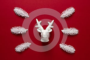 White reindeer with white pine tree branches on red backdrop. Minimal New Year or Christmas background concept