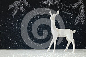 White reindeer on wooden table over chalkboard background with hand drawn chalk illustrations