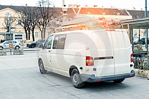 White repair and service van with ladder and orange light bar on roof at city street. Assistance or installation team vehicle