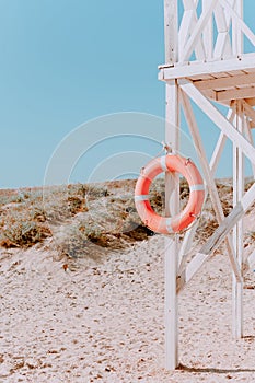 White rescue post with a lifebuoy. on a Sunny summer day. Coastal architecture. Wooden rescue post against the blue sky