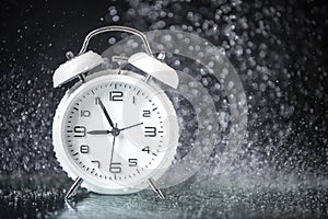 White retro alarm clock in a black background under the water drops.. Morning. Break. Motivation. Business solutions. Success.