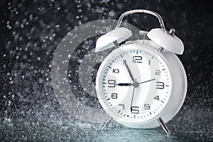 White retro alarm clock in a black background under the water drops.. Morning. Break. Motivation. Business solutions. Success.