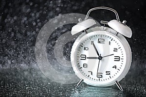 White retro alarm clock in a black background under the water drops.. Morning. Break. Motivation. Business solutions. Success.