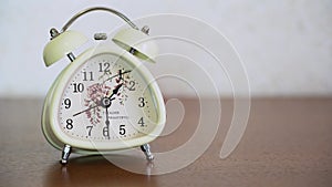 White retro alarm o-clock with bells stand on a brown wood table on blurred background close up. Classic old bell shows