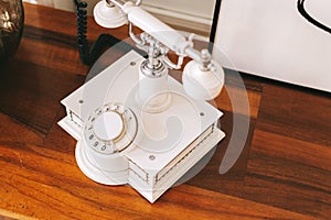 White retro telephone on a wooden table. Close-up