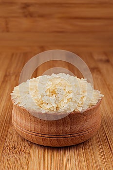 White rice basmati in wooden bowl on brown bamboo board, closeup. Healthy dietary cereals background.