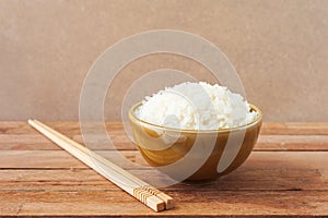 White rice in brown bowl with wooden chopsticks