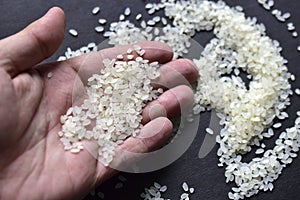 White rice grains in the palm of your hand on a black background