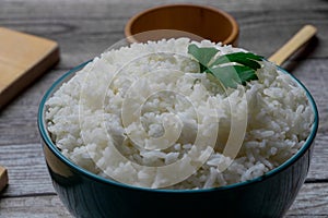 White rice in a green colored bowl and kitchen utensils