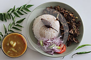 White rice meal along with fried bitter gourd and onion tomato salad called challas served with Sambar