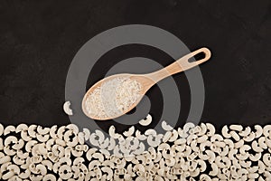 White rice in wooden spoon and Healthy gluten-free pasta products made from rice flour. Dark textured background, copy space