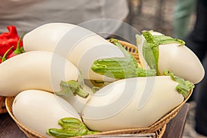 White ripe fresh eggplant lying in a wicker basket at the farmers market. Elite and modern varieties and hybrids of vegetables