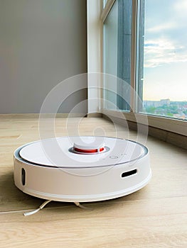 White robot cleaner. Robot vacuum cleaner on laminate floor in action