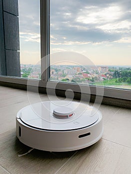 White robot cleaner. Robot vacuum cleaner on laminate floor in action