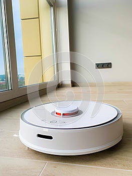 White robot cleaner. Robot vacuum cleaner on laminate floor in action