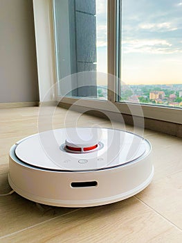 White robot cleaner. Robot vacuum cleaner on laminate floor in action