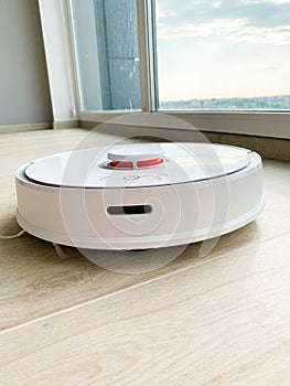 White robot cleaner. Robot vacuum cleaner on laminate floor in action