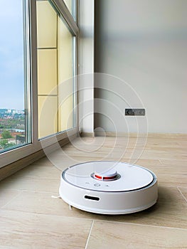 White robot cleaner. Robot vacuum cleaner on laminate floor in action