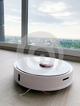 White robot cleaner. Robot vacuum cleaner on laminate floor in action