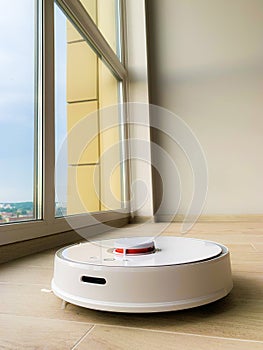 White robot cleaner. Robot vacuum cleaner on laminate floor in action