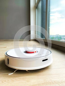 White robot cleaner. Robot vacuum cleaner on laminate floor in action