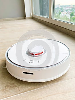 White robot cleaner. Robot vacuum cleaner on laminate floor in action