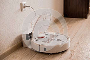 White robot vacuum cleaner on the floor in interior