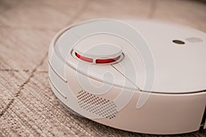 White robot vacuum cleaner on the floor in interior