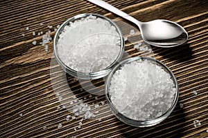 White rock coarse salt in glass bowls on brown wooden table