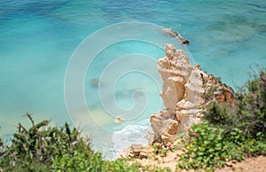 White rock and green plants against the blue water of the Atlantic Ocean in Algarve, Portugal, Europe