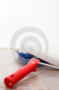 White roller and paint tray, white wall in the background