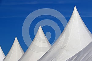 White roofs of tents aligned over blue sky