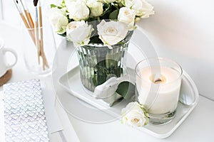 White room interior decor with burning hand-made candle and bouq