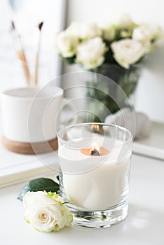 White room interior decor with burning hand-made candle and bouq