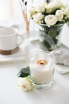 White room interior decor with burning hand-made candle and bouq