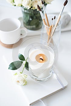 White room interior decor with burning hand-made candle and bouq