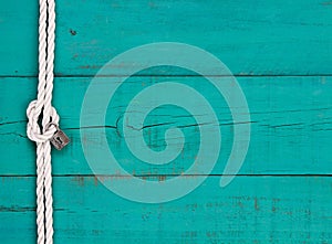 White rope with know and silver lock on rustic teal blue sign