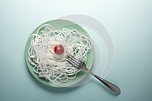 White rope with a red tomato and a fork on a round plate. Spaghetti concept