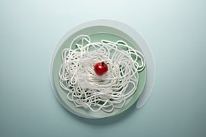 White rope with red tomato on a round plate. Spaghetti concept