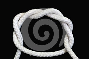 A white rope tied with double overhand knot on black background