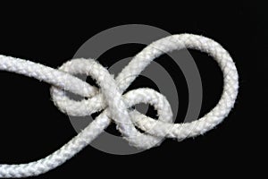 A white rope tied with running bowline knot on black background