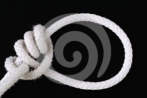A white rope tied with tarbuck knot on black background