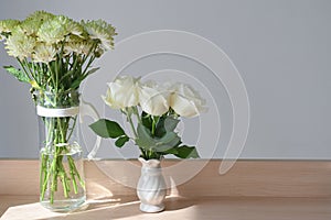 White rose blossom decoration in home, beautiful flower blooming in small vase put on wooden table with sunlight