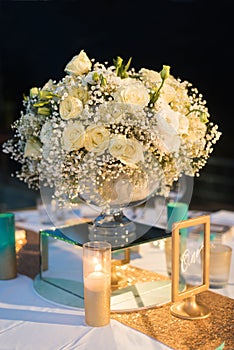 White rose bouquet set up on reception night wedding with boken at night.