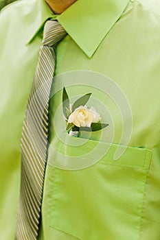 White rose boutonniere on green suit of the groom