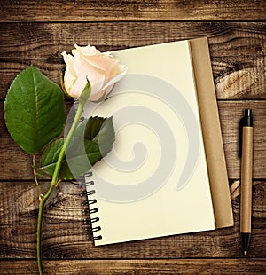 White rose flower with notebook and pen
