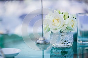White rose in the glass pot on the table
