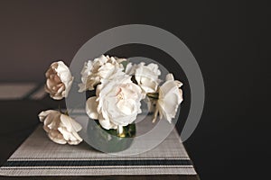 white roses bouquet in glass jar on gray table runner and kitchen table